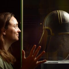 Adult poses with the 'York Helmet' in Yorkshire Museum's 'Capital of the North' exhibition.